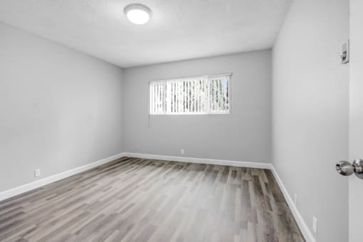 the living room of an empty house with wood flooring and a window