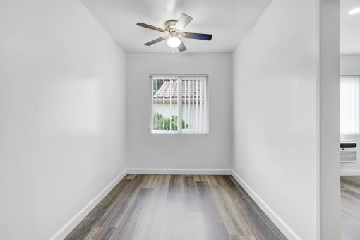 an empty room with a window and a ceiling fan