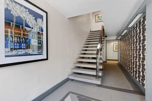 a staircase leading up to a hallway with a painting on the wall and a staircase