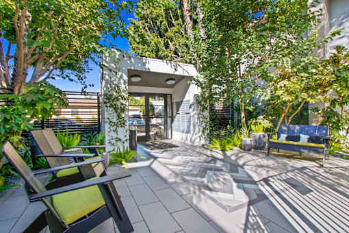 a patio with chairs and trees and a house in the background