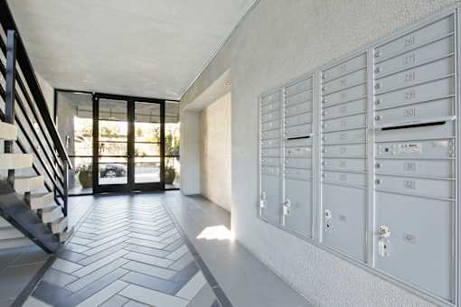 a long hallway with white cabinets and a staircase and glass doors