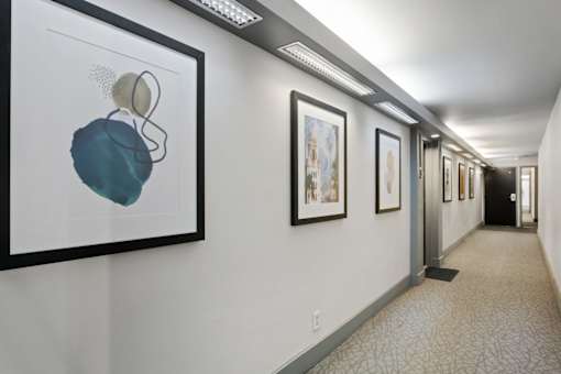 a hallway with pictures on the wall and a corridor with elevators