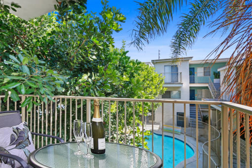 a bottle of wine on a table on a balcony overlooking a swimming pool