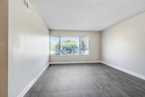 an empty living room with a window and wood floors