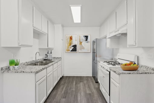 a white kitchen with marble counter tops and stainless steel appliances