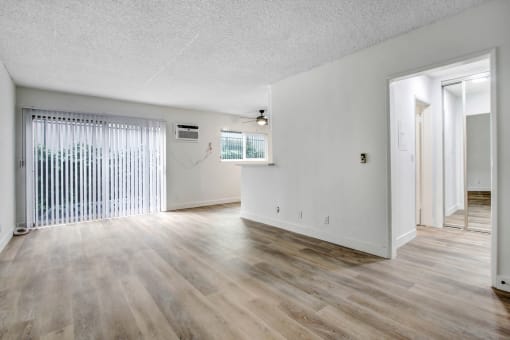 an empty living room with hardwood floors and a large window