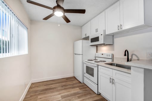 a kitchen with white appliances and a ceiling fan