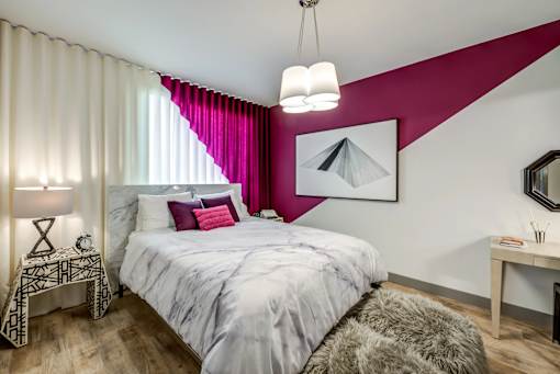 A bedroom with a large bed and a pink accent wall.