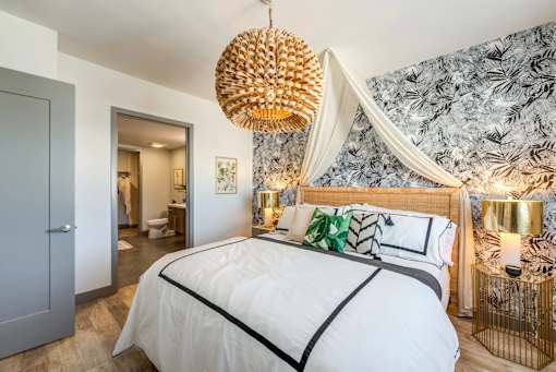 A bedroom with a large bed and a chandelier hanging from the ceiling.