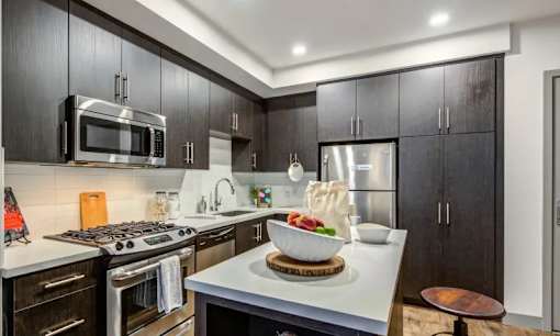 A modern kitchen with black cabinets and a white countertop.
