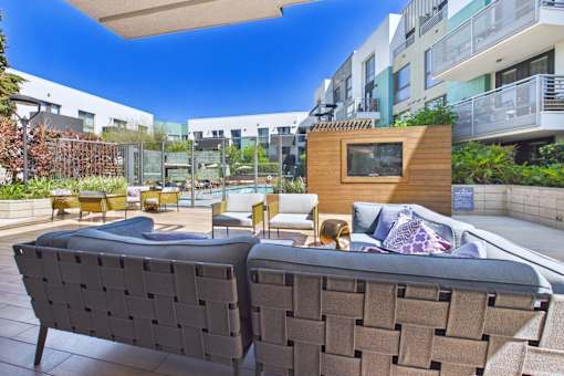 A modern outdoor seating area with a large couch and a small wooden structure.