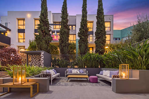 A modern outdoor seating area with a fire pit and cushioned benches.