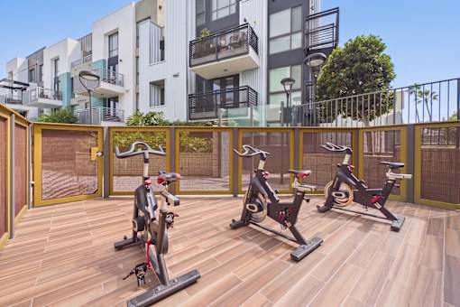 A wooden deck with three stationary bikes on it.