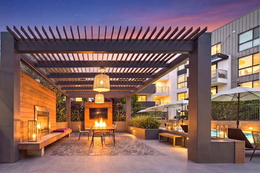 A patio with a fireplace and chairs under a pergola.