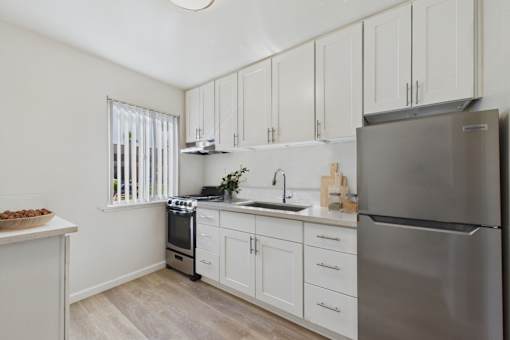 A kitchen with white cabinets and a stainless steel refrigerator.