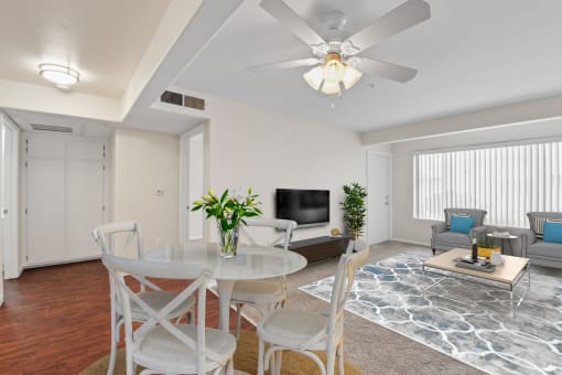 a living room with white furniture and a ceiling fan