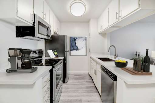 A modern kitchen with a refrigerator, microwave, and coffee maker.
