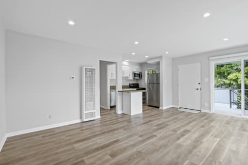 A spacious kitchen with a refrigerator, microwave, and a dining table with chairs.