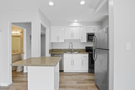 A modern kitchen with a granite countertop and stainless steel appliances.