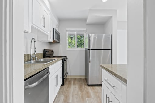 A modern kitchen with white cabinets and stainless steel appliances.