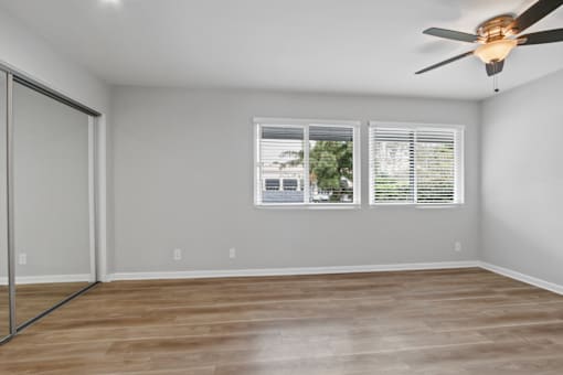 A room with a ceiling fan and a window with blinds.
