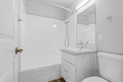 A white bathroom with a toilet, sink, and bathtub.