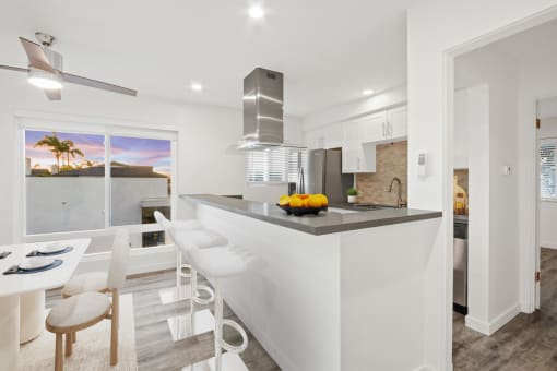 a white kitchen with a bar and a dining area