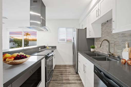 a kitchen with stainless steel appliances and a bowl of fruit on the counter