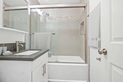 a white bathroom with a shower and a sink