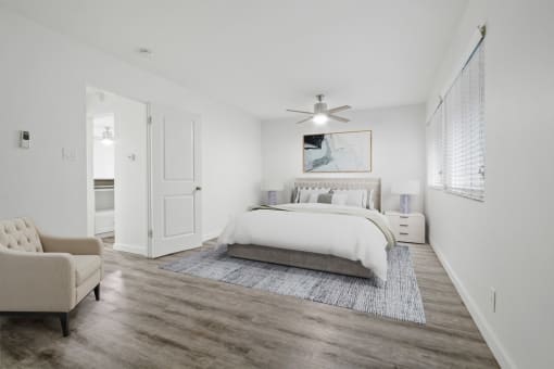 a white bedroom with a bed and a ceiling fan