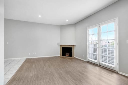 an empty living room with a fireplace and wooden floors