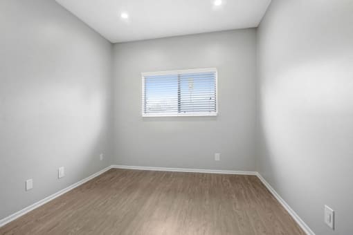 the living room of an empty home with wood floors and a window