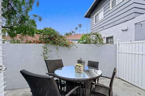 a patio with a table and chairs in front of a house