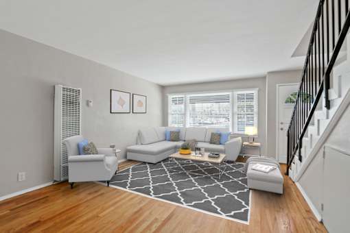 a living room with couches and a rug in front of a staircase