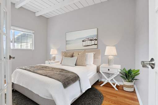 a bedroom with a bed and a white table with two lamps