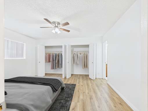 A bedroom with a bed, a ceiling fan, and a wardrobe.