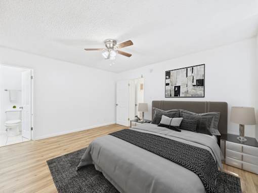 A bedroom with a bed, nightstands, and a ceiling fan.