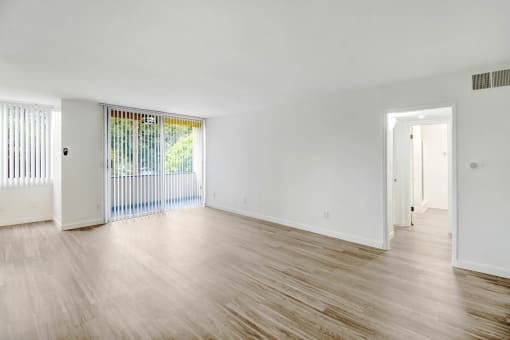 the living room and dining room of an empty house with wood floors and white walls