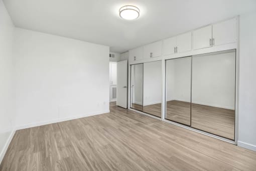 an empty room with white walls and mirrored closet doors