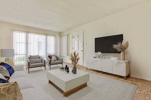 A living room with a white sofa, grey armchairs, a white coffee table, and a black television.