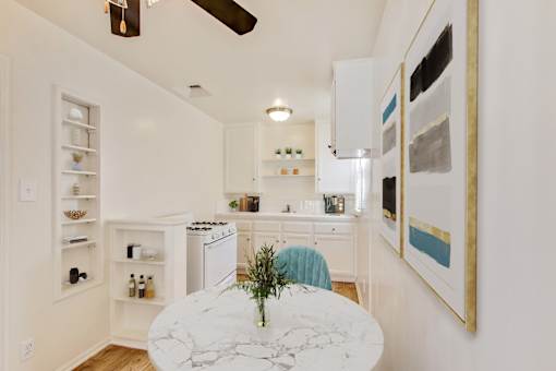 A kitchen with a marble table and a ceiling fan.