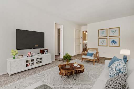 A living room with a white couch, a wooden coffee table, and a flat screen TV.
