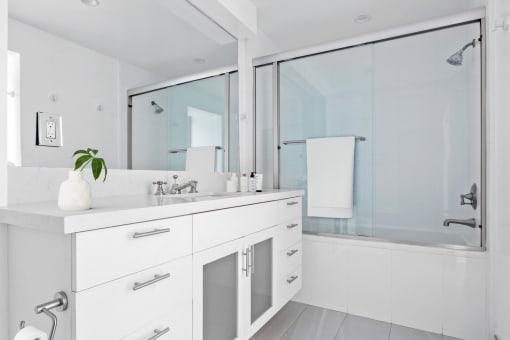 a white bathroom with a large mirror and a sink and a shower