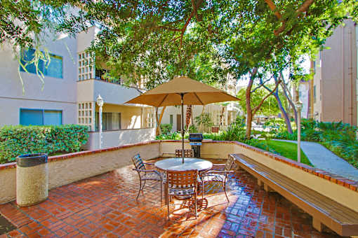 Resort-like picnic and barbecue area with wood bench, lush landscaping