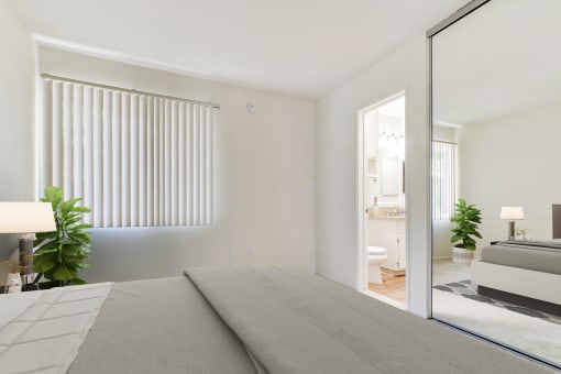 a white bedroom with a bed and a bathroom