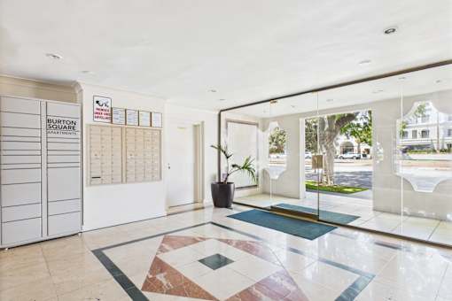 The Burton Square Apartments lobby features a large tiled floor and a glass wall with a view of the outside.