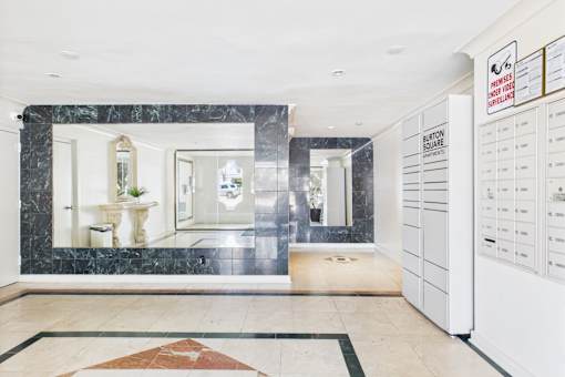 A white reception desk with a sign that says "BURTON SQUARE" is in the middle of a room with a marble floor.