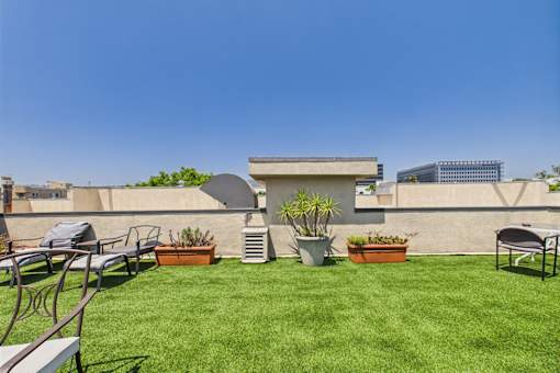 A backyard with a lawn, chairs, and potted plants.