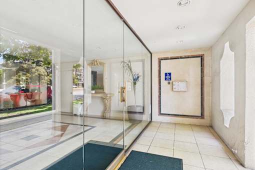 A hallway with a glass wall and a green rug on the floor.
