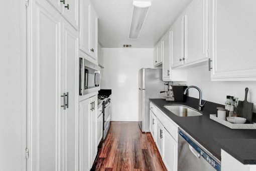 a kitchen with white cabinets and a wood floor